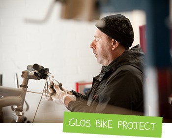An image of a man fixing a bike, with the caption Glos Bike Project